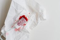 A used tampon with red stains on a crumpled white tissue for health awareness.