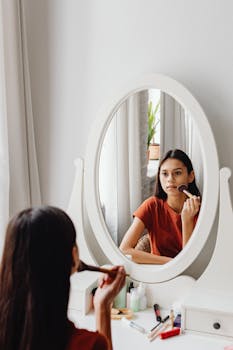 Teen girl applying makeup with brush in a bright room.