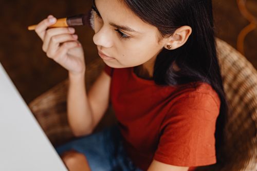 Free High angle view of a young woman applying makeup with a brush indoors. Stock Photo