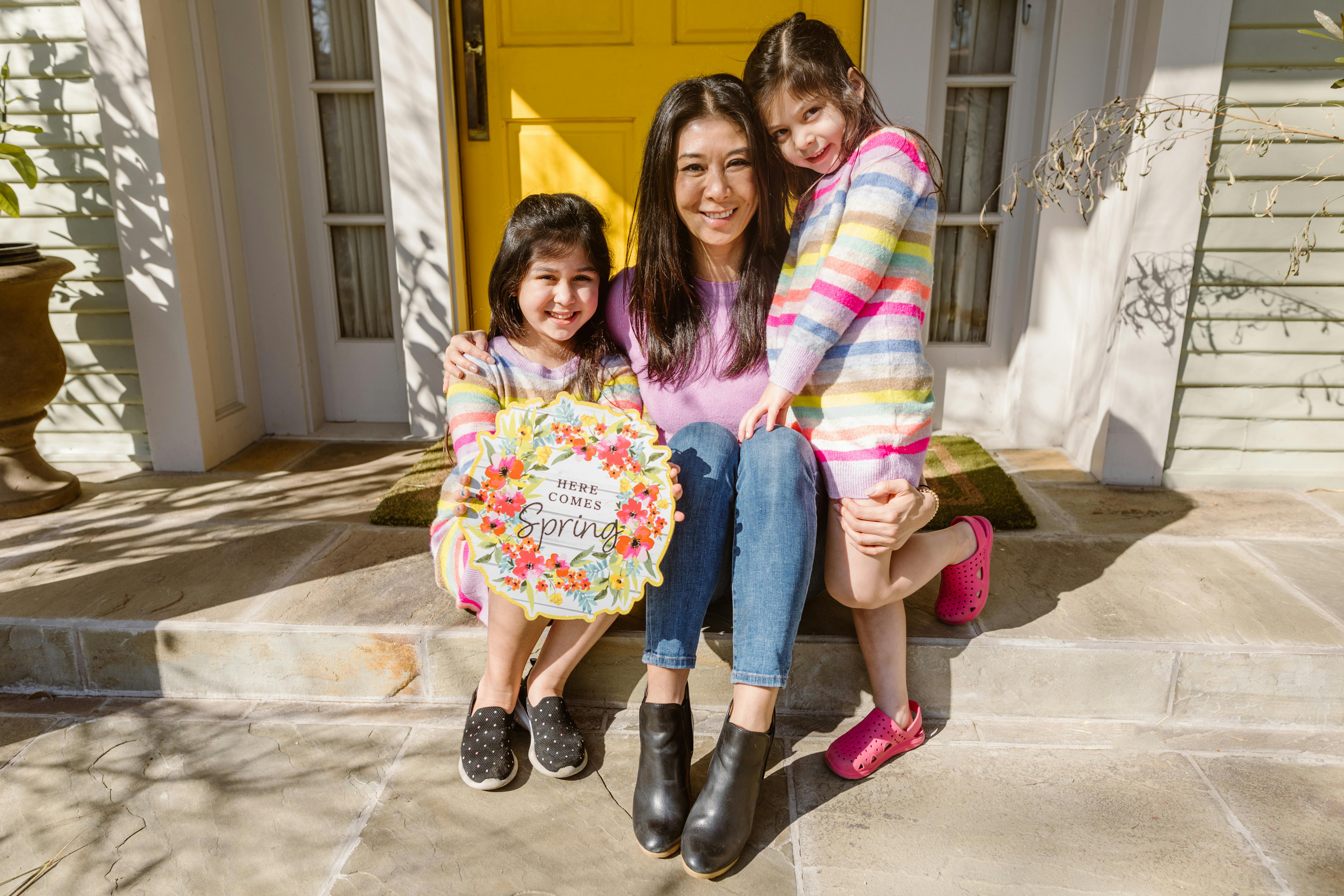 mother and two daughters sitting outside the front door