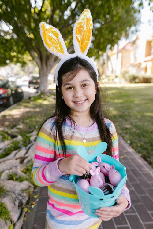 Free Young girl with bunny ears and Easter basket outdoors, smiling brightly. Stock Photo