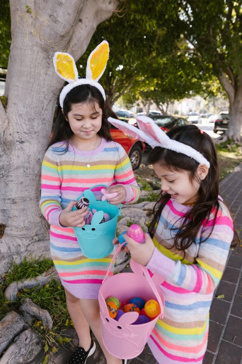 Free Two children wearing bunny ears gather Easter eggs in colorful baskets during a fun outdoor hunt. Stock Photo