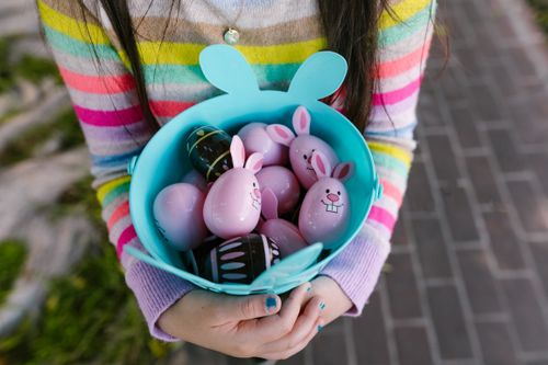 Free A child holds a colorful basket filled with Easter eggs during springtime. Stock Photo