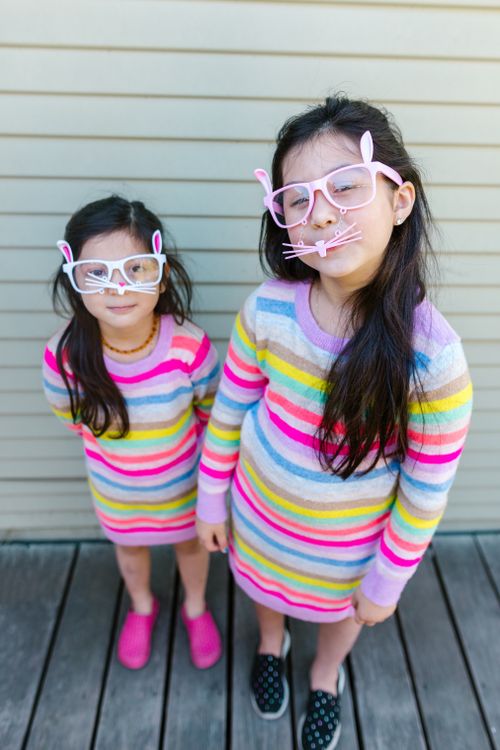 Free Adorable sisters in striped dresses and bunny glasses, celebrating a joyful spring day. Stock Photo