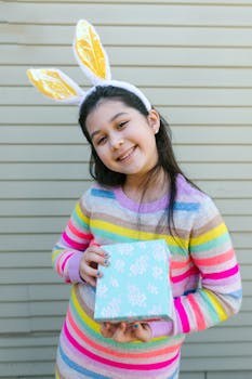 Happy girl wearing bunny ears and holding a gift box, perfect for Easter celebrations.