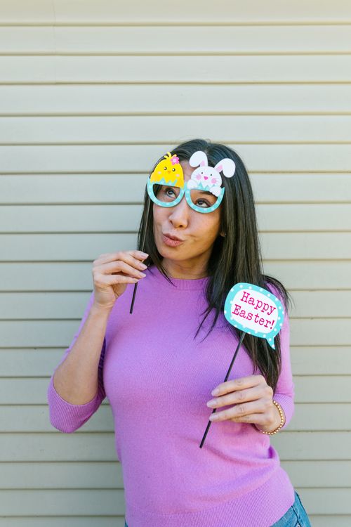 Free Woman in purple sweater holding playful Easter props with a joyful expression. Stock Photo