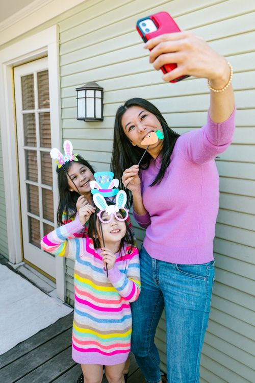 Free A mother and her daughters taking a cheerful Easter selfie with bunny props on a sunny spring day. Stock Photo
