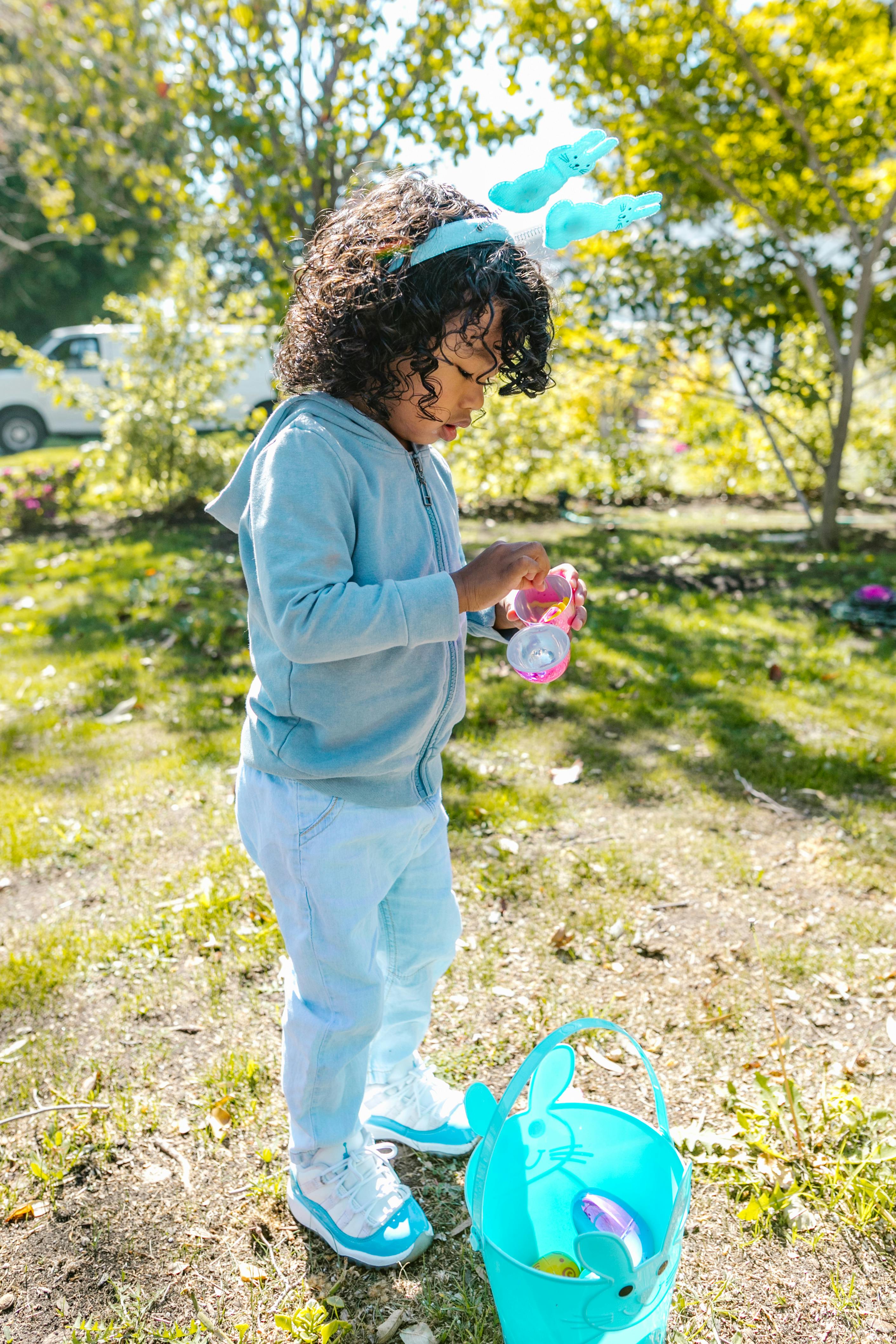 A young child participates in a joyful Easter egg hunt on a sunny day.