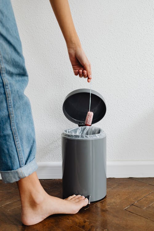 Person Throwing Trash in Waste Bin