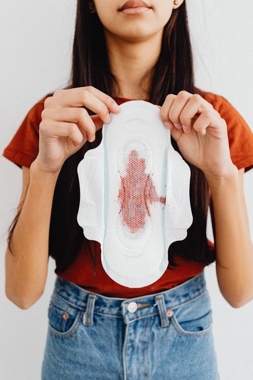 Free Close-up of a woman holding a menstrual pad with a blood stain, highlighting menstruation. Stock Photo
