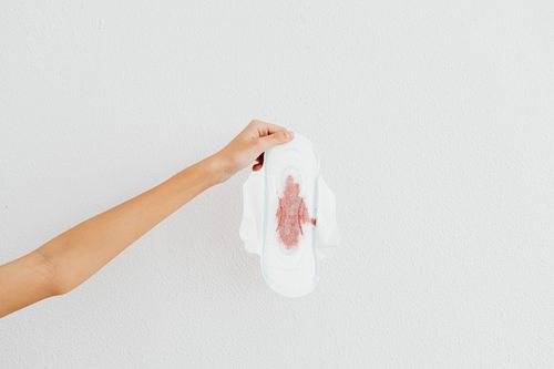 Free A hand holding a menstrual pad with blood stains, emphasizing menstruation awareness. Stock Photo