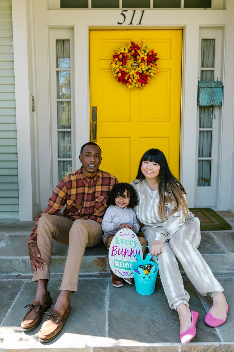 Family sitting together at their front door, which has a yellow door and a wreath