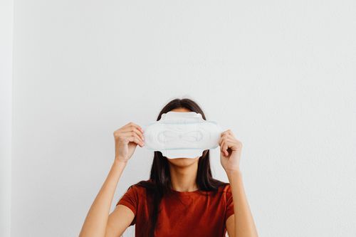 Free Woman concealing face with a sanitary pad against a white background. Stock Photo
