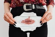 Close-up view of a woman holding a stained menstrual pad, emphasizing menstruation awareness.