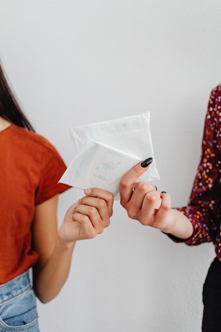 Close-Up Shot Of Two People Holding Sanitary Napkins In A Pack