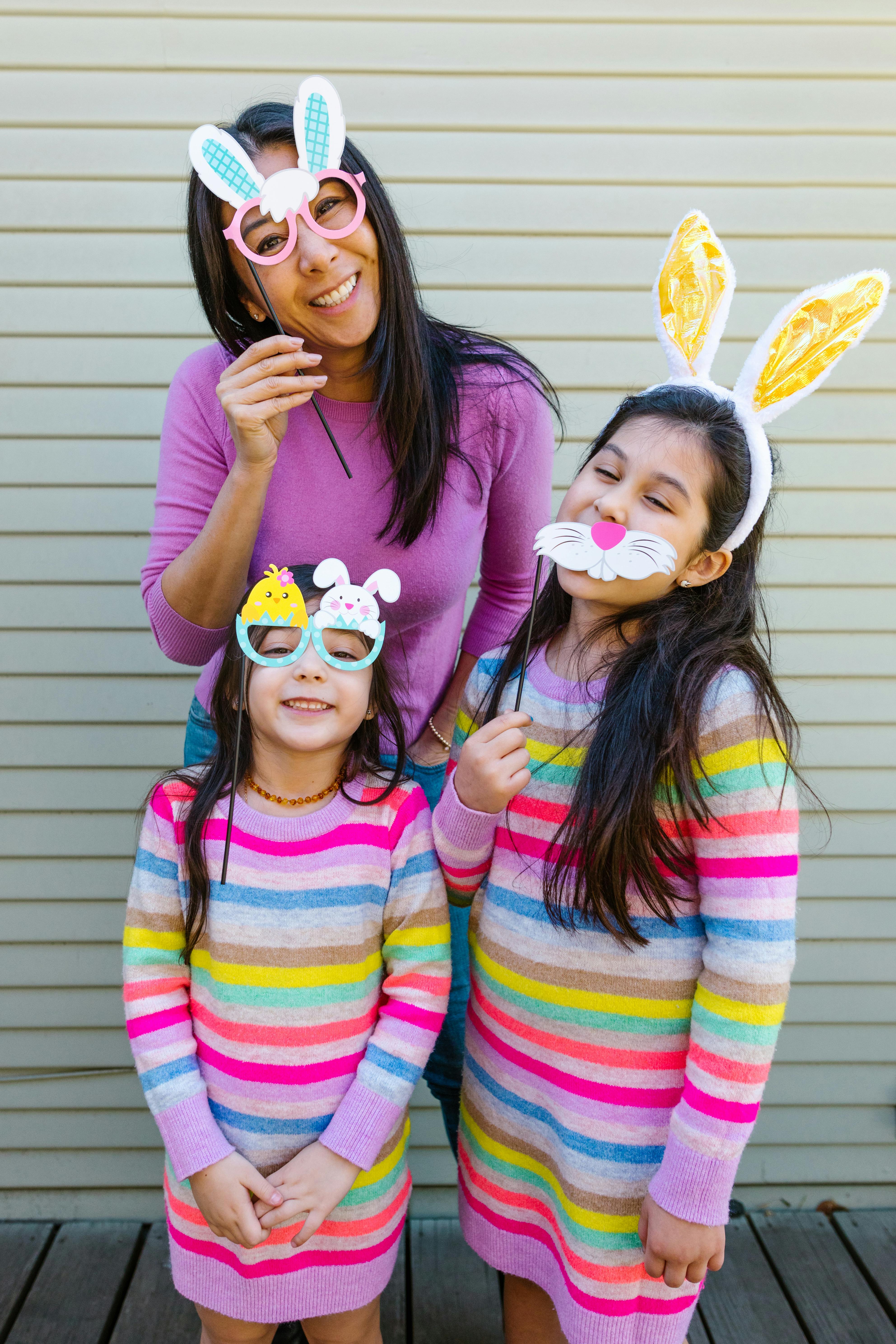 Mother and daughters wearing bunny ears and glasses, celebrating Easter with joy.