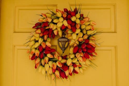 Red and Yellow Floral Wreath Hanging on a Yellow Door