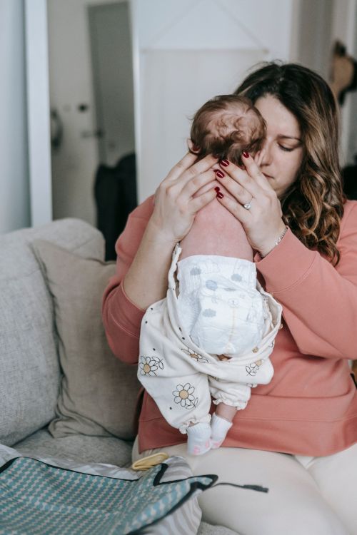 Free A mother lovingly holds her baby in a nurturing home setting, showcasing parenthood's early days. Stock Photo