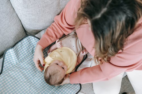 Woman in Pink Long Sleeve Shirt Carrying Baby