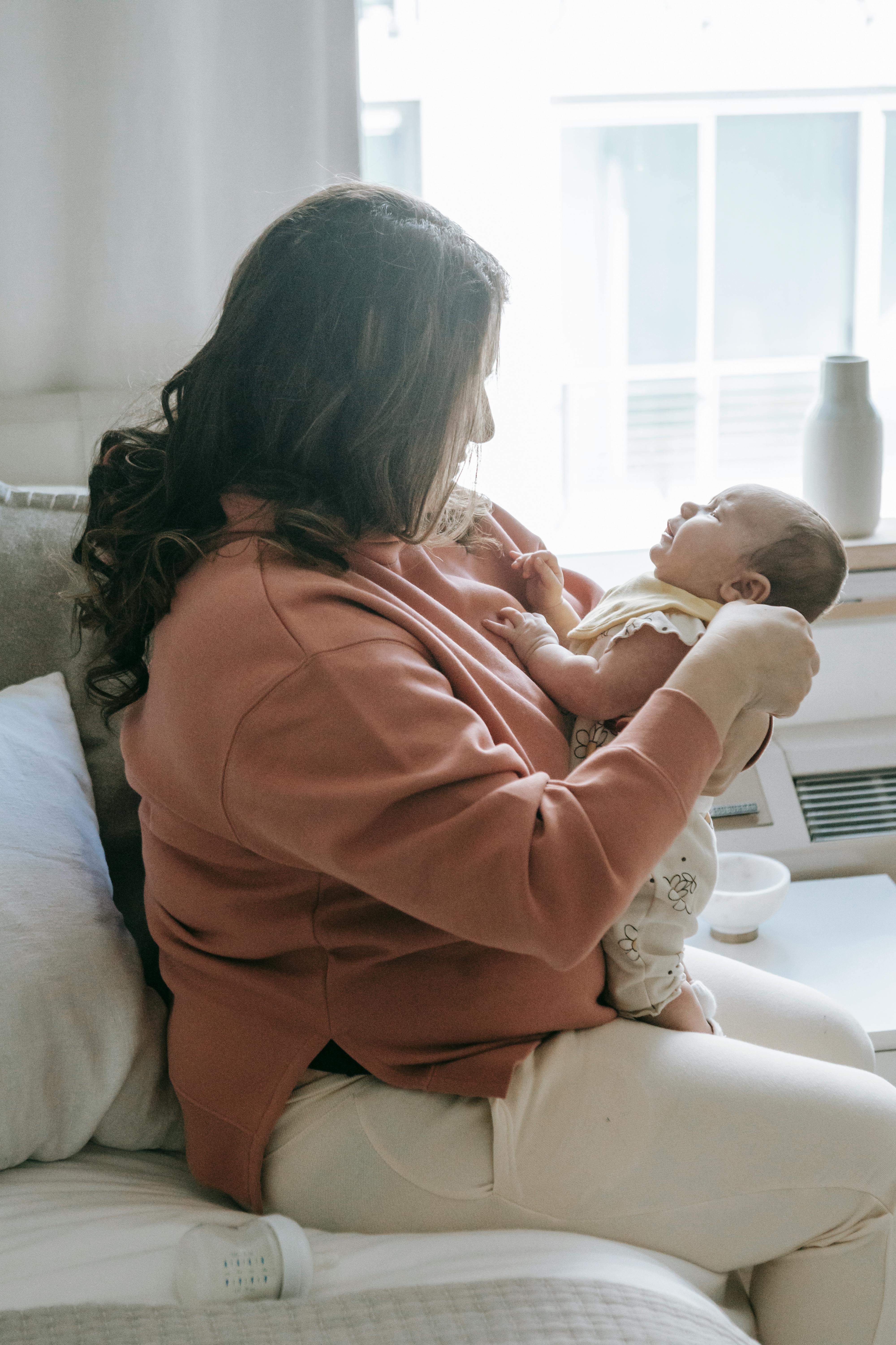 woman in sweater carrying a baby