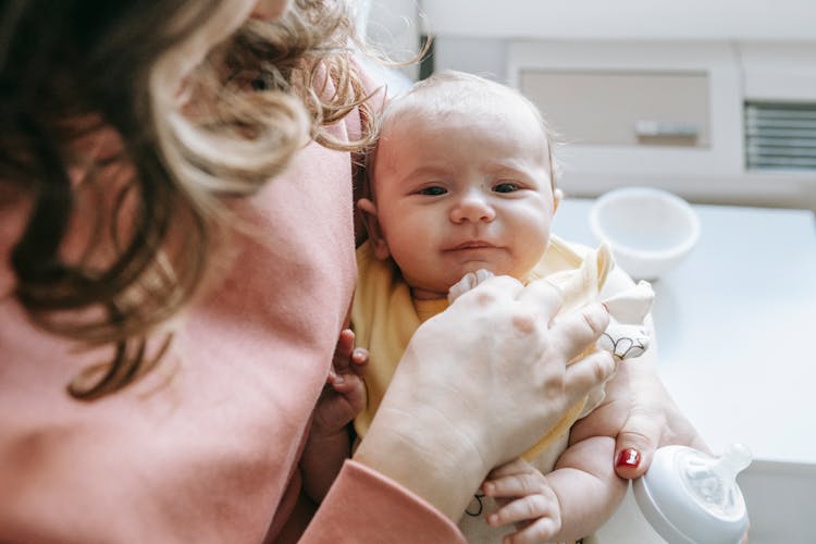 Mother Holding Cute Baby And Bottle