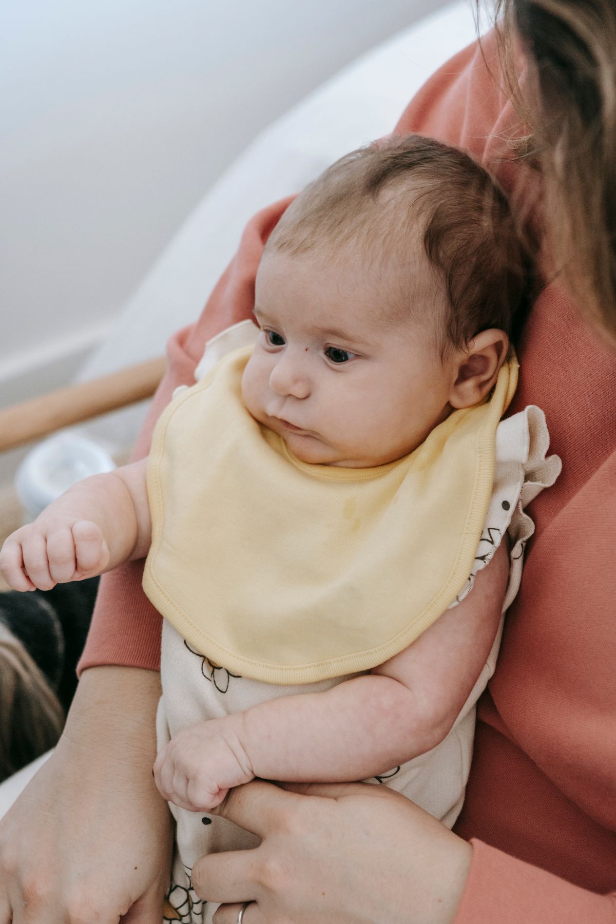 A mother at home holding her baby close against her chest