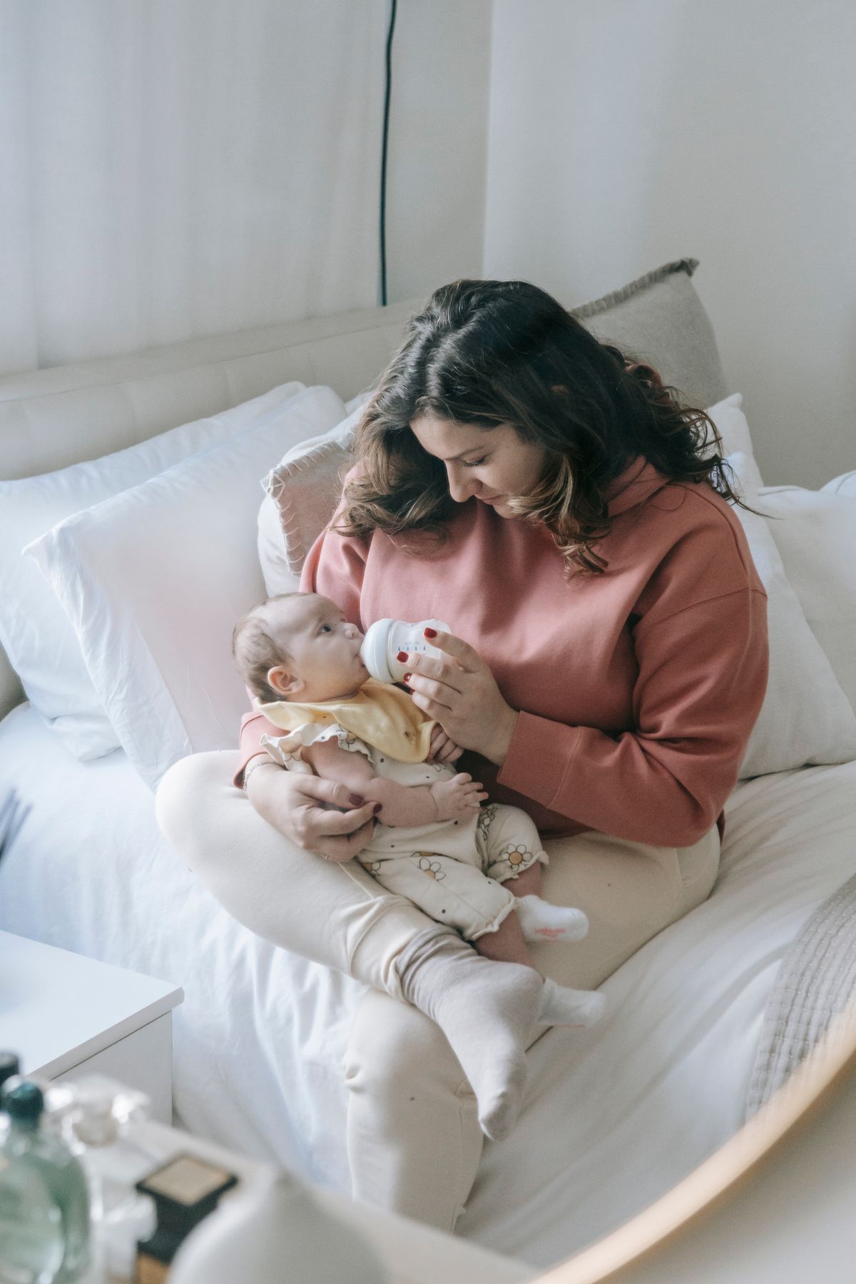Mother gently feeding her baby with a bottle at home