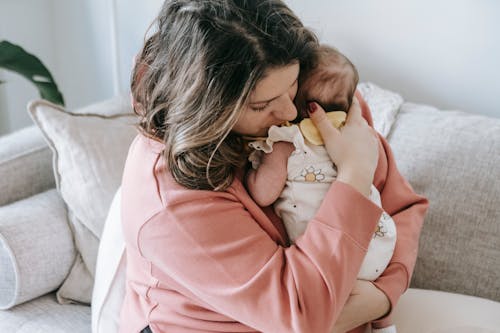 Mother embracing baby tenderly in bedroom