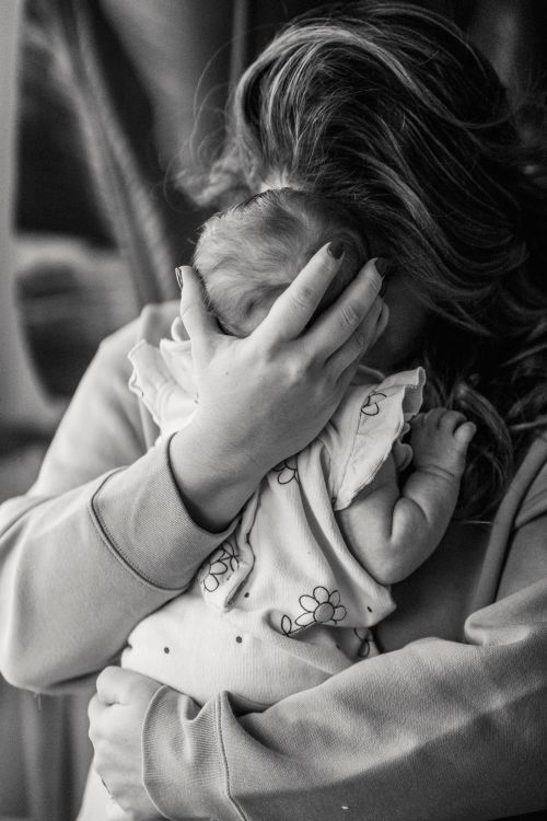 Free Black and white of unrecognizable caring mother embracing little faceless newborn baby in arms while standing in room at home Stock Photo