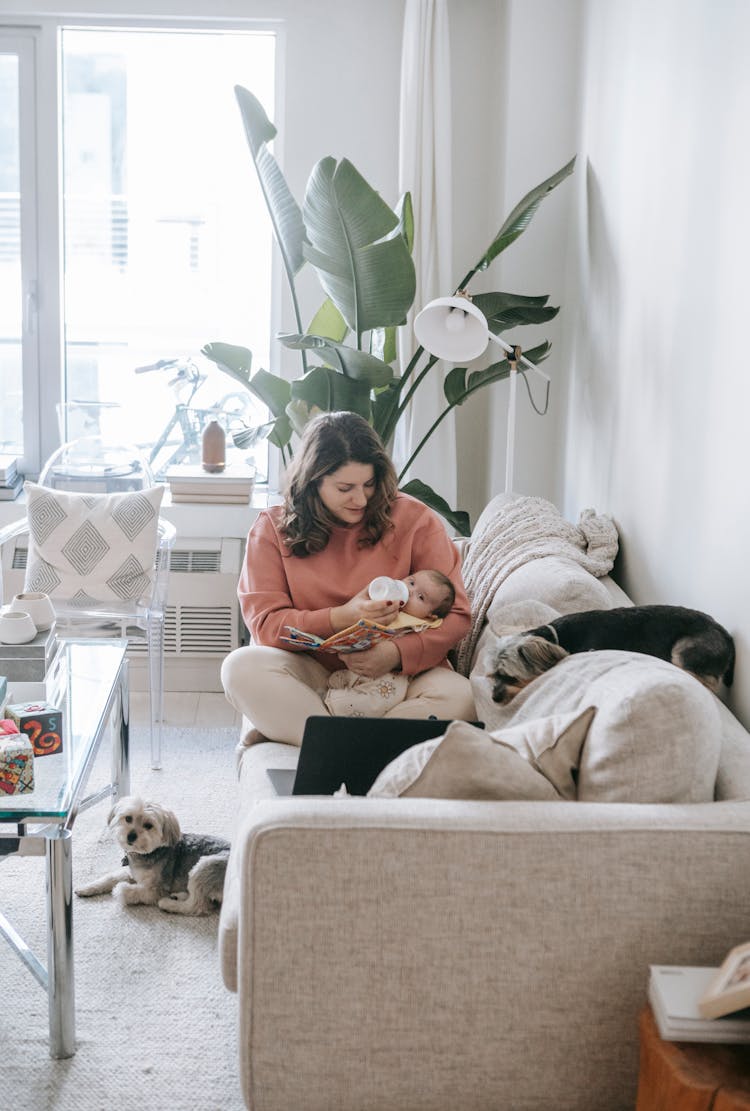 Woman Feeding Baby On Couch In Room