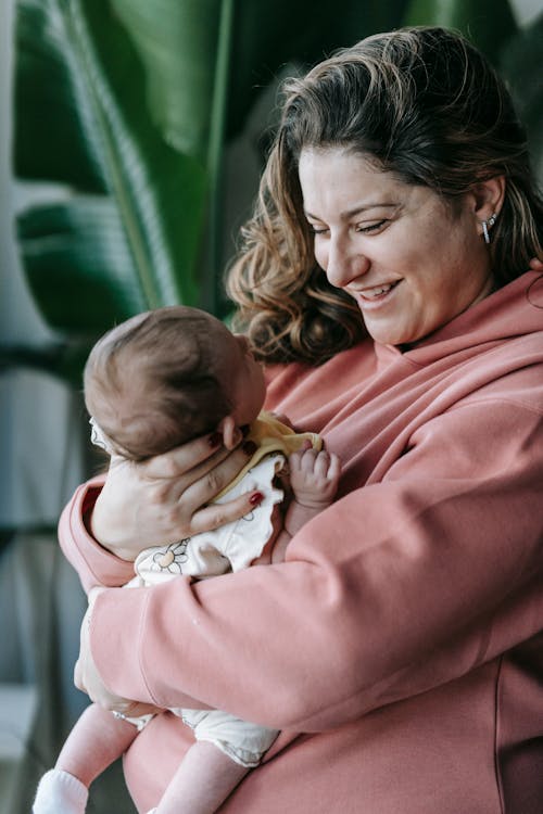 Cheerful mother with newborn baby in arms