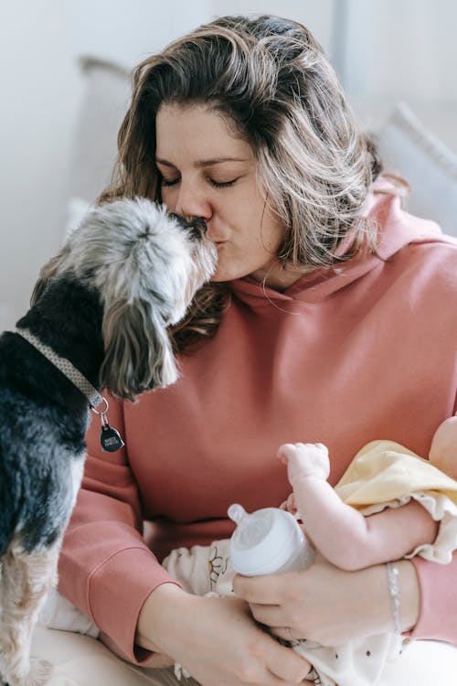 Woman with faceless baby caressing dog
