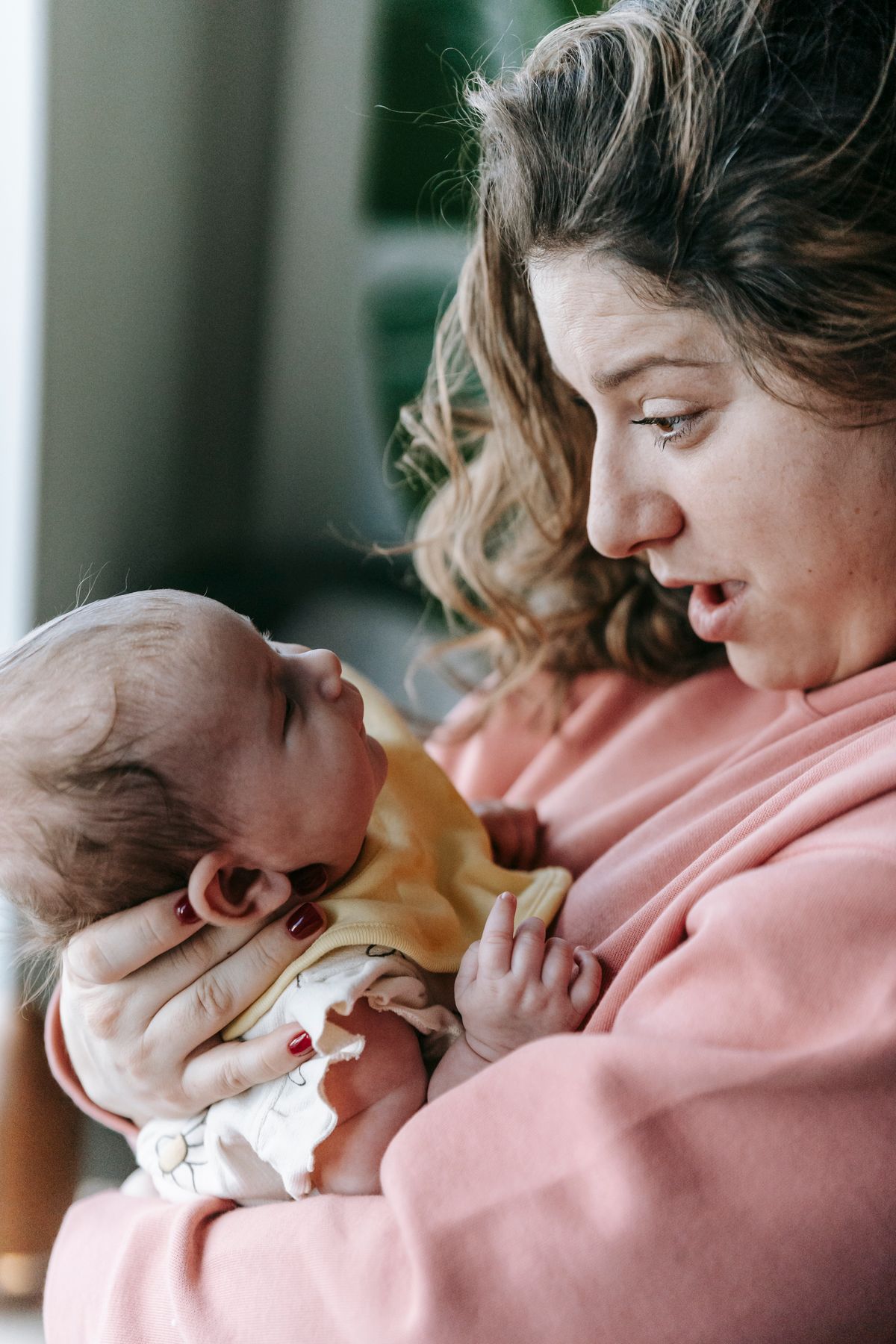 Mom holding her newborn in front of her, making faces and talking to them