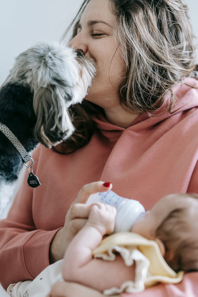 Woman Caressing Dog While Feeding Baby