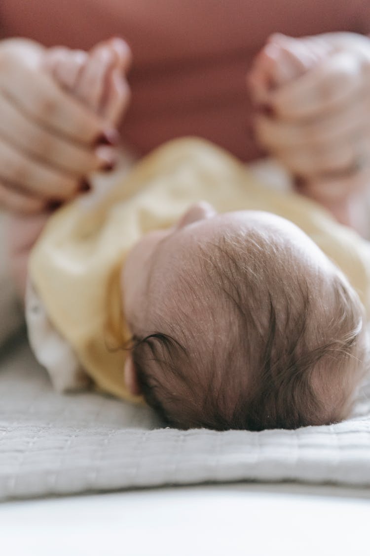 Crop Mother Playing With Infant Lying On Changing Table