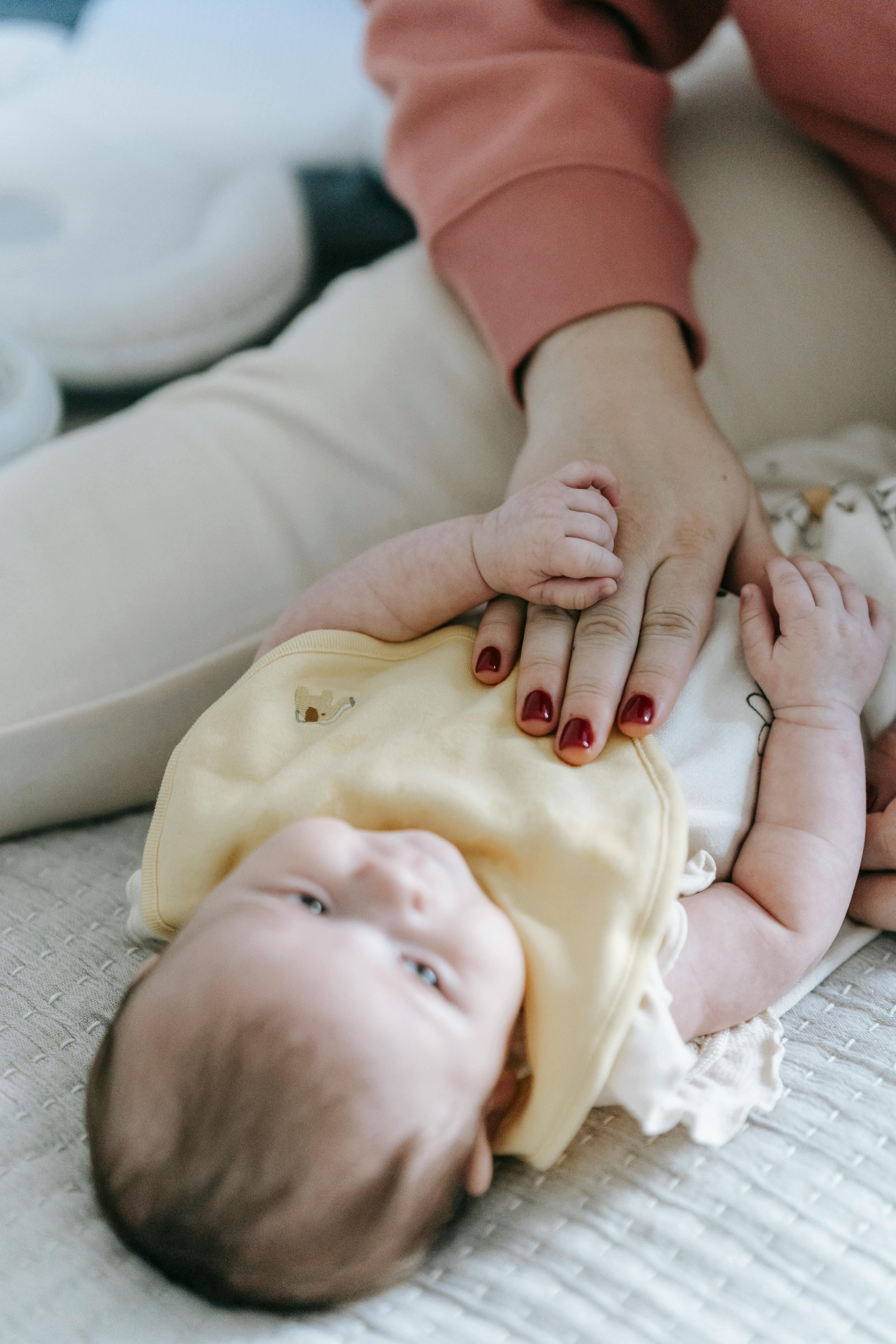 crop unrecognizable mother massaging infant belly on bed