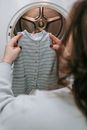 Anonymous woman with baby clothes near washing machine