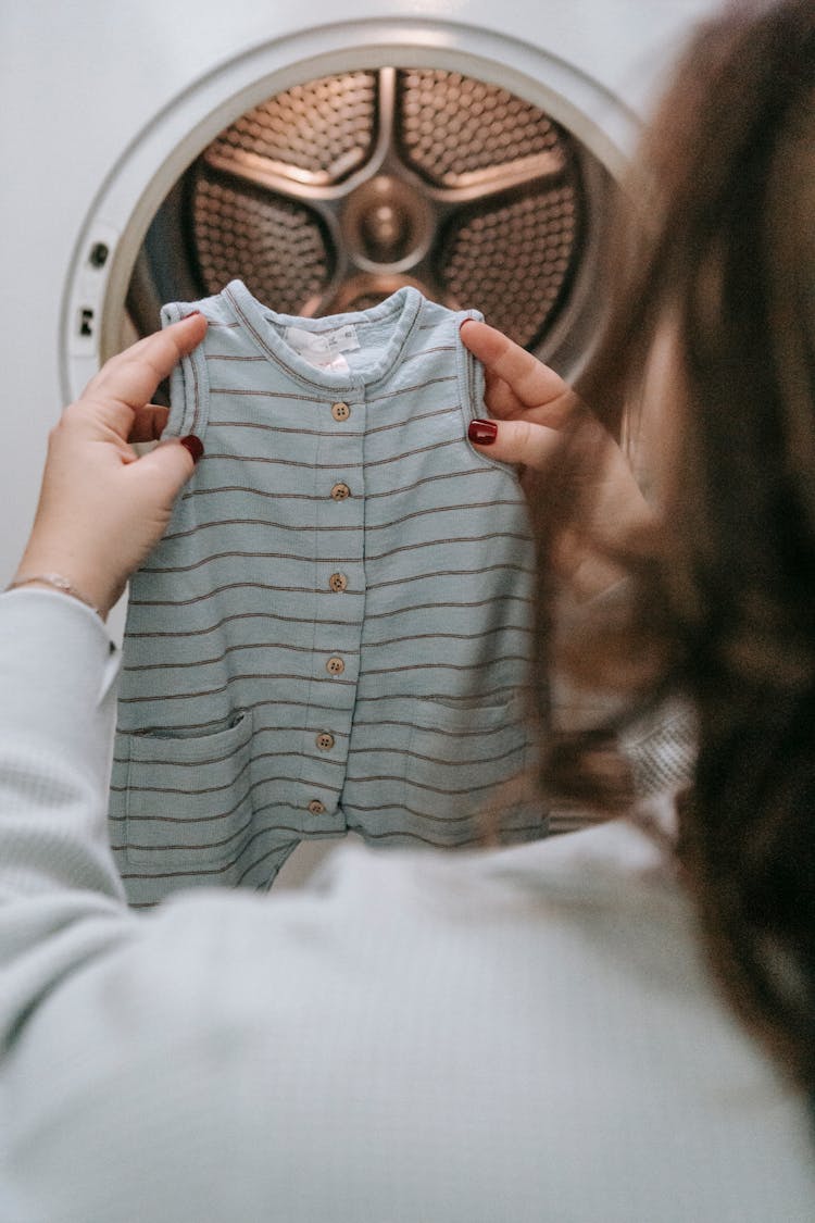 Anonymous Woman With Baby Clothes Near Washing Machine