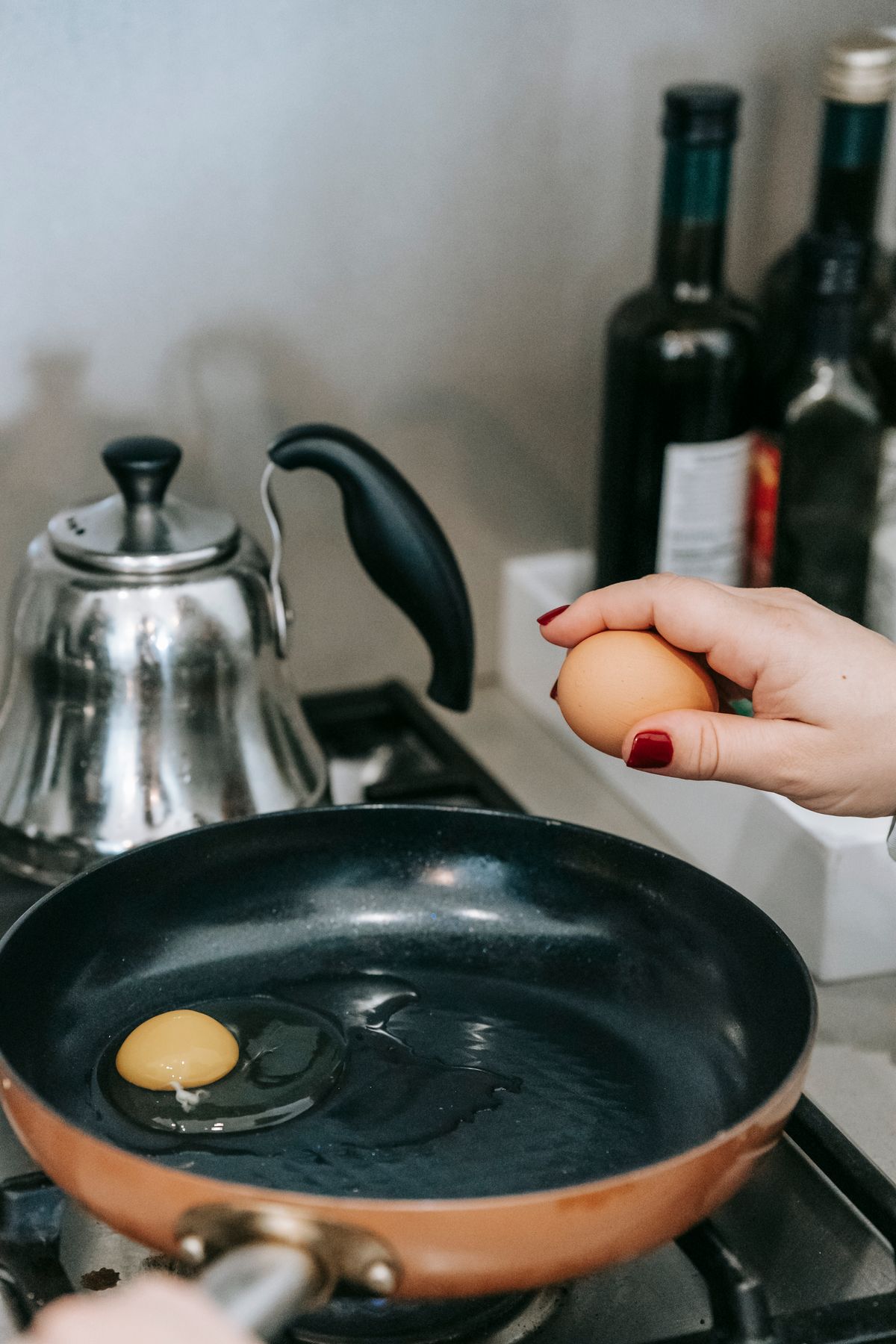 Pessoa preparando ovo em uma frigideira na cozinha