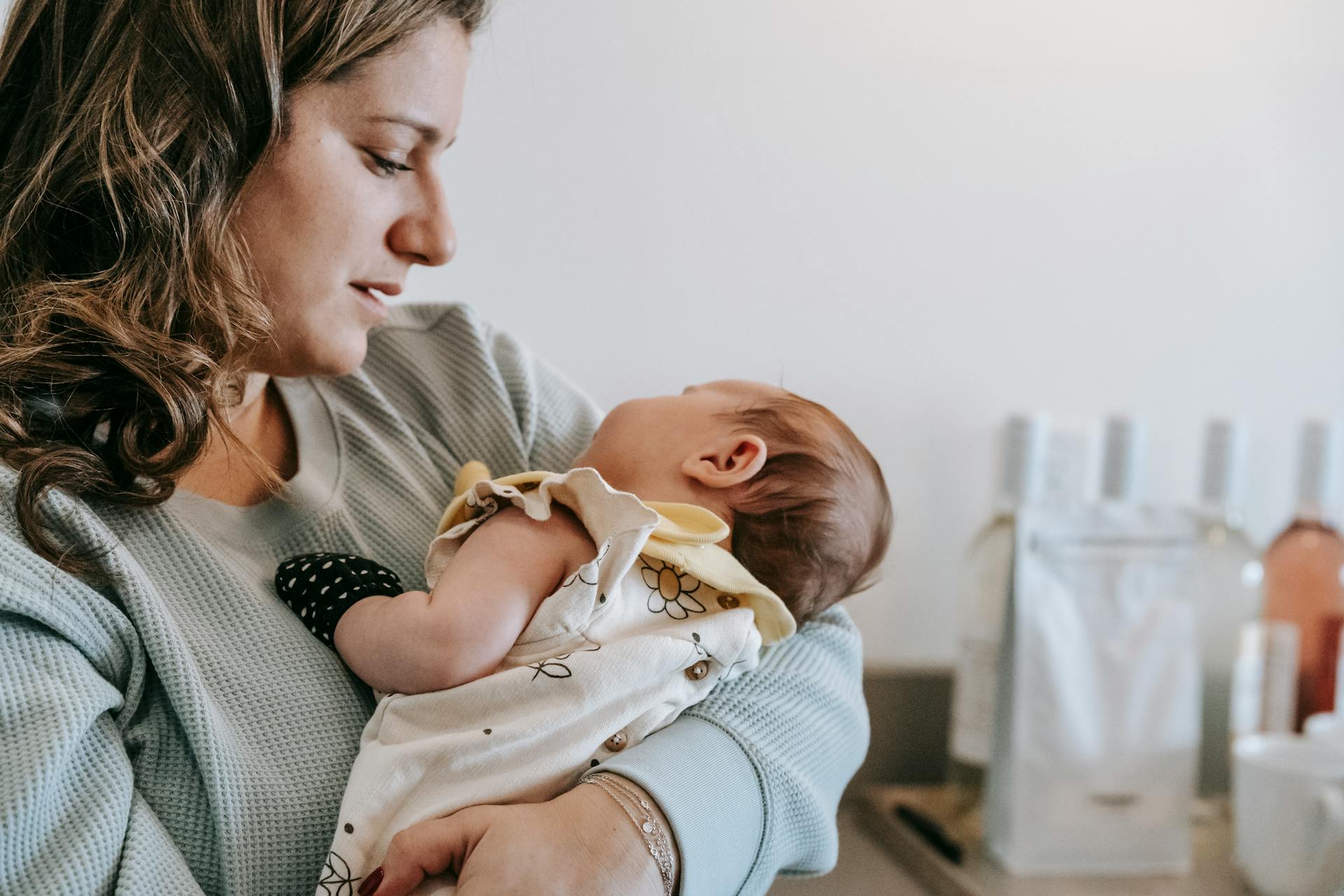 A tender moment between mother and newborn at home, capturing warmth and love indoors.