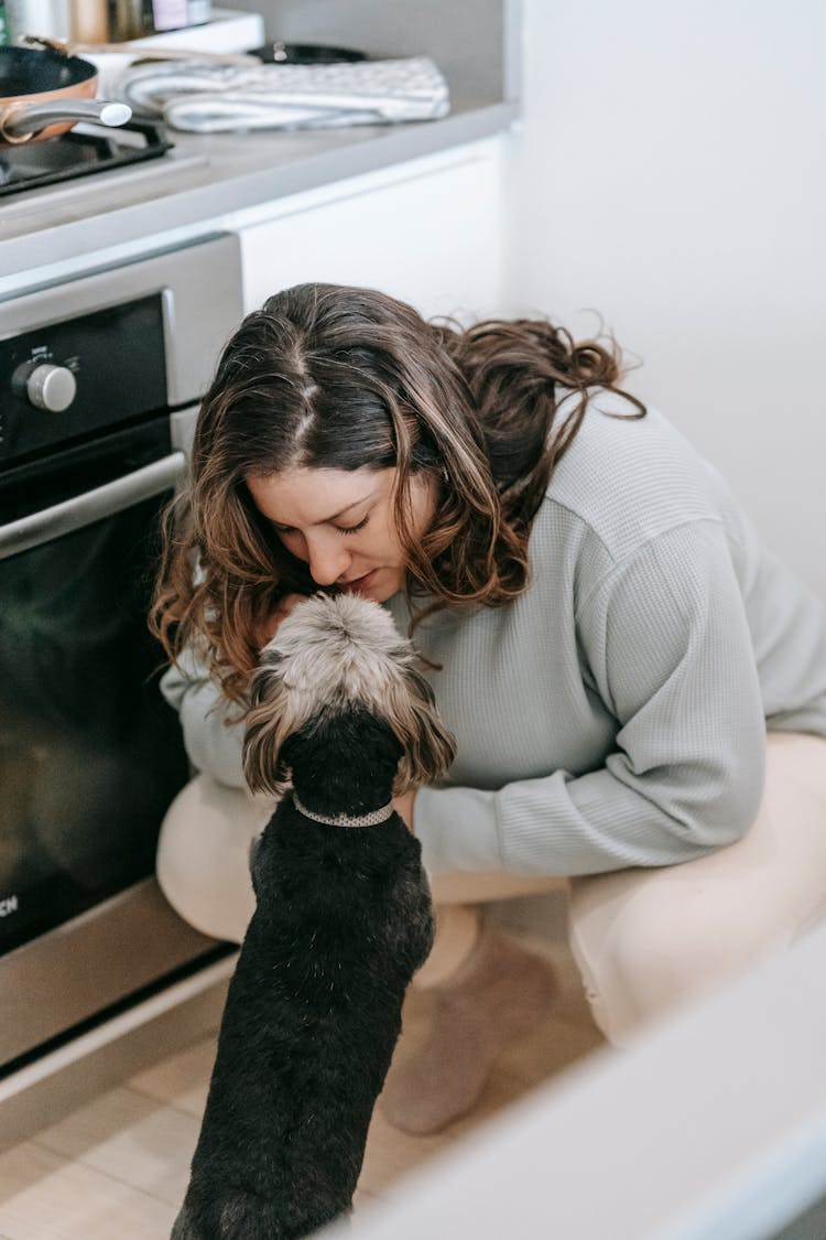 Woman Caressing Dog In Kitchen