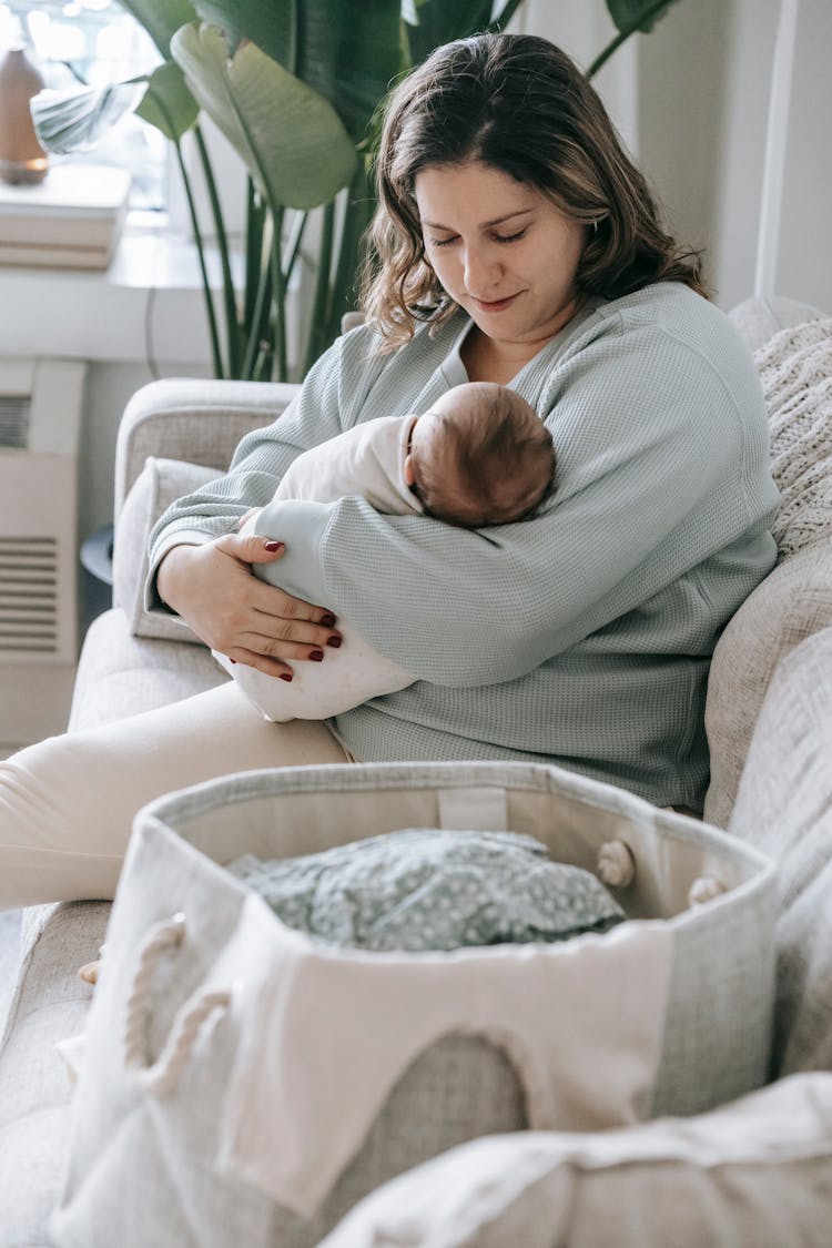 Mother With Newborn Baby On Couch