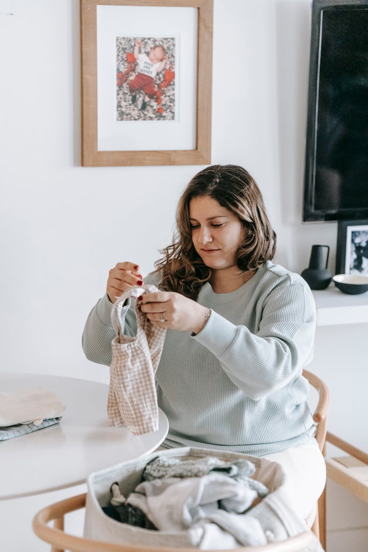 Woman With Baby Clothes At Table