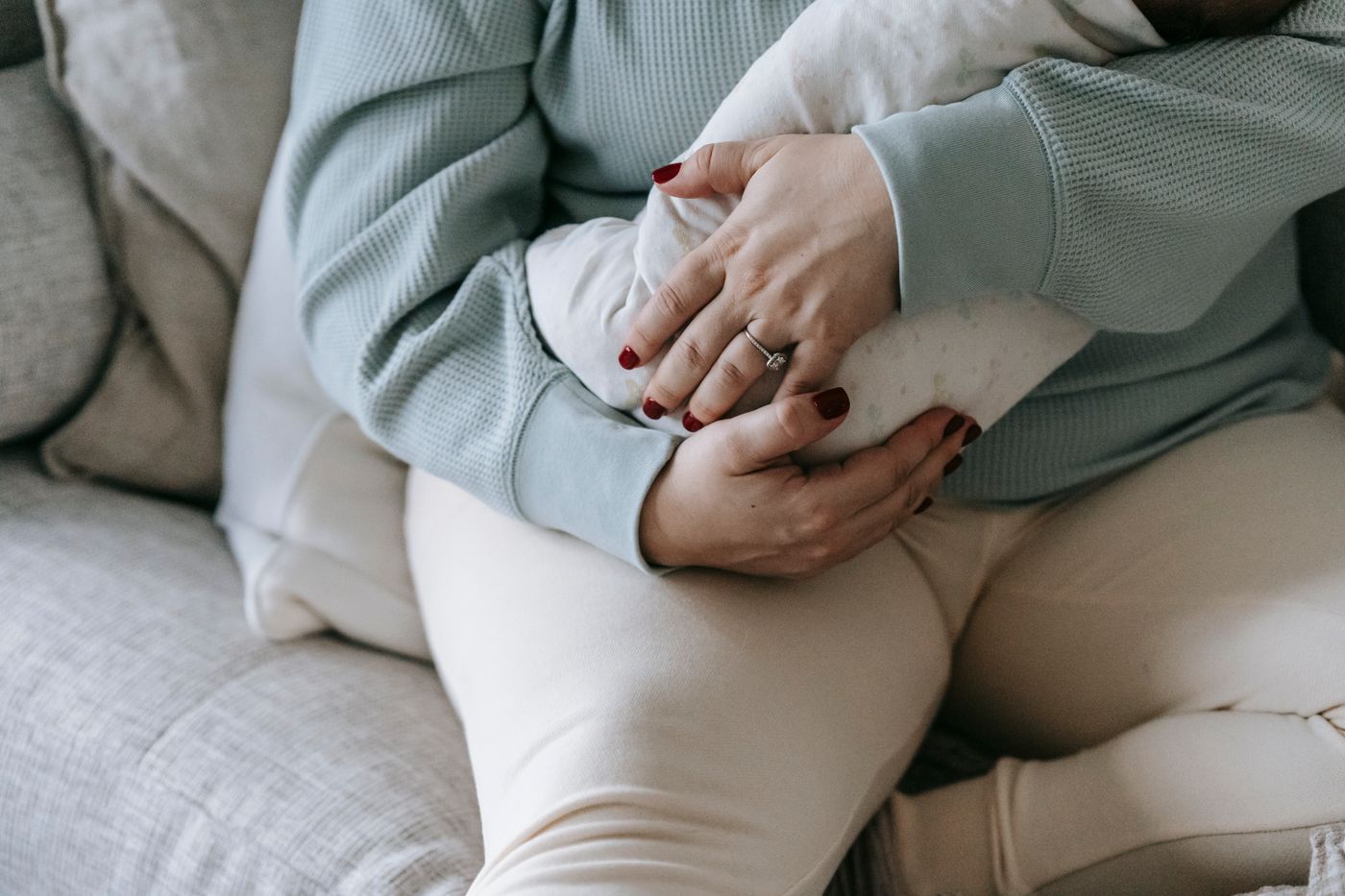 Maman habillée tenant paisiblement son bébé dans ses bras dans un salon lumineux