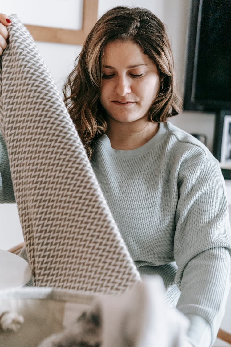 Focused Woman Folding Scarf In Room