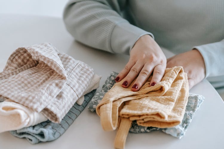 Unrecognizable Woman Folding Baby Clothes