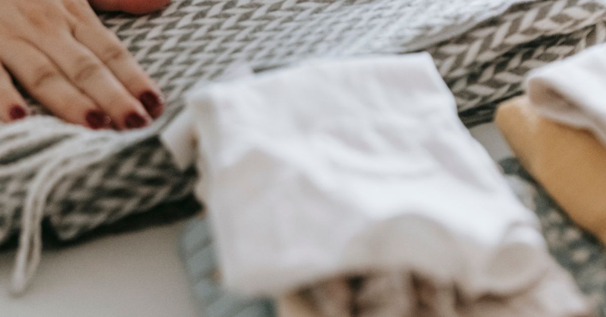 Dobrando roupas de bebê Close das mãos de uma mulher dobrando roupas