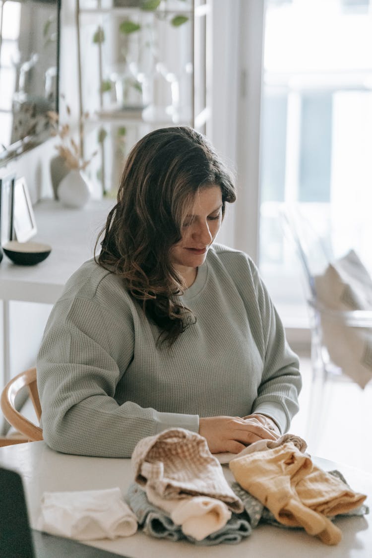 Woman Folding Baby Clothes At Table