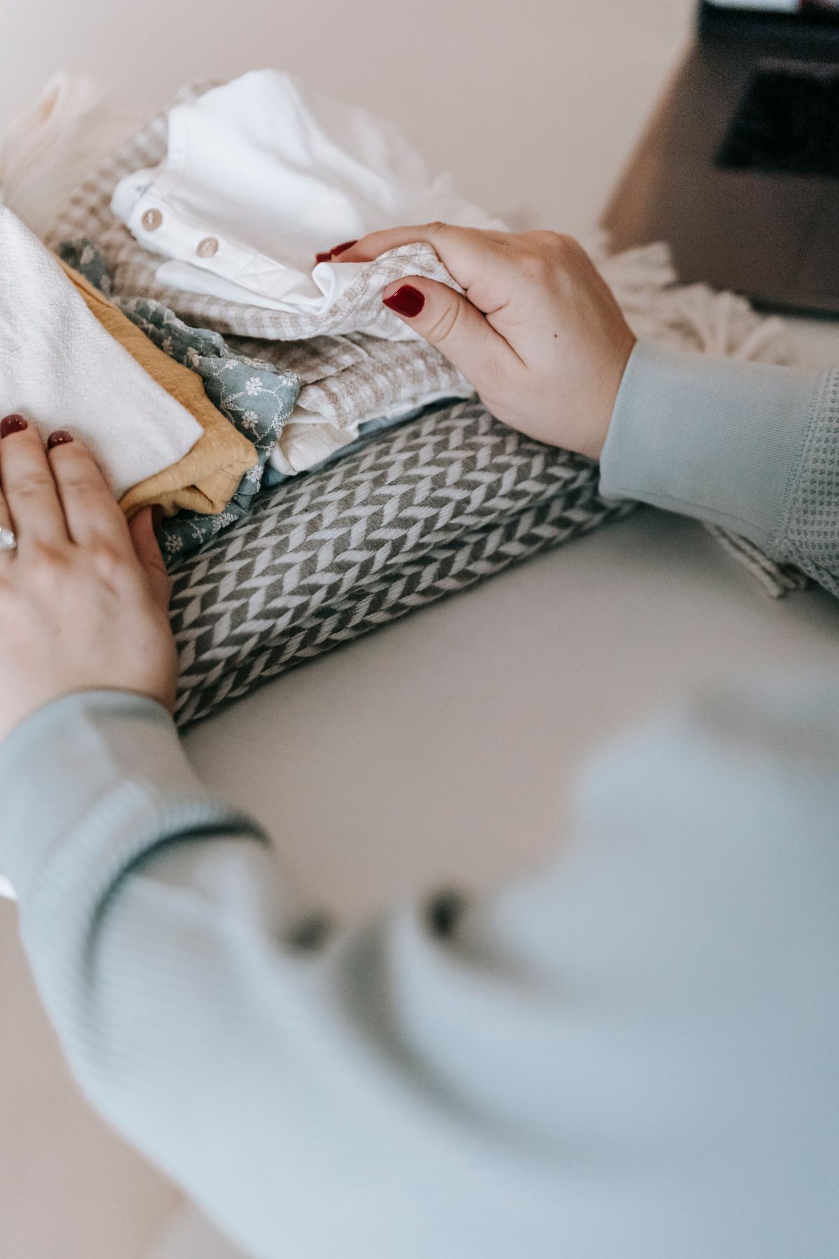 Mãos dobrando roupas em casa como tarefa doméstica curta para organizar sem sobrecarga