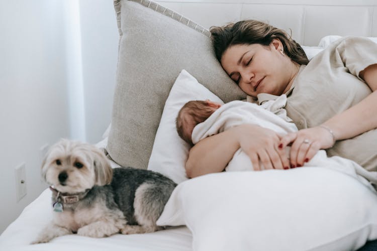 Mother With Infant Baby Sleeping Near Dog